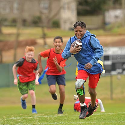 Three boys playing flag football. One has a prosthetic leg