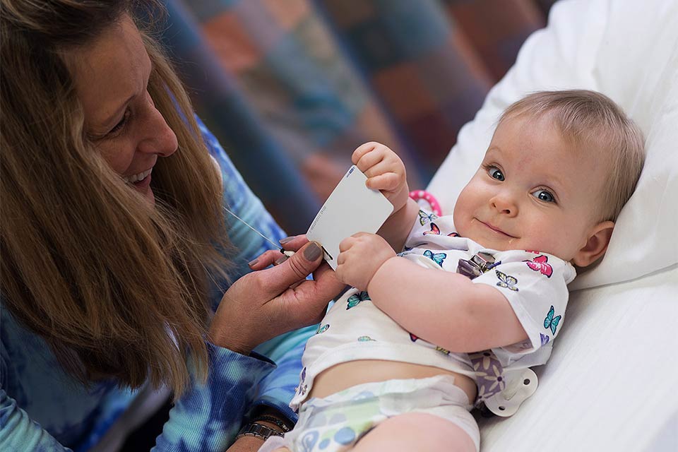 Baby on exam table with therapist next to her