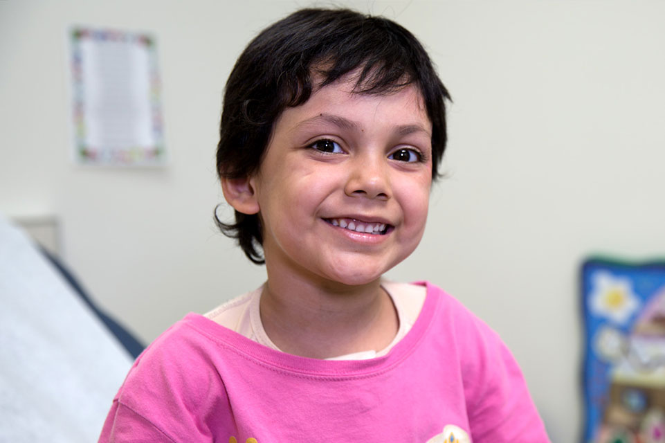 une jeune fille souriante à la caméra avec t-shirt rose