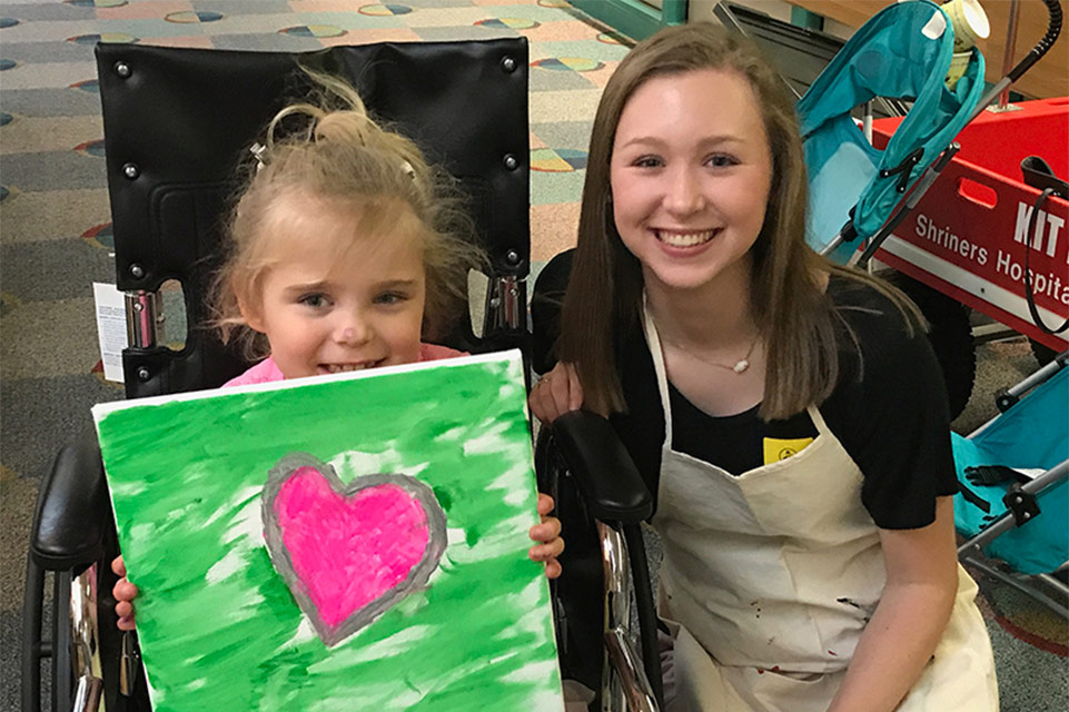 female patient displaying artwork with therapist