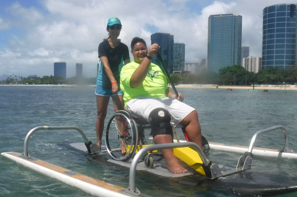 un patient en fauteuil roulant sur une planche à pagaie adaptée