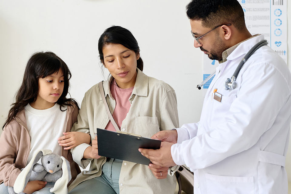 Médico mostrando una historia clínica a una mamá e hija