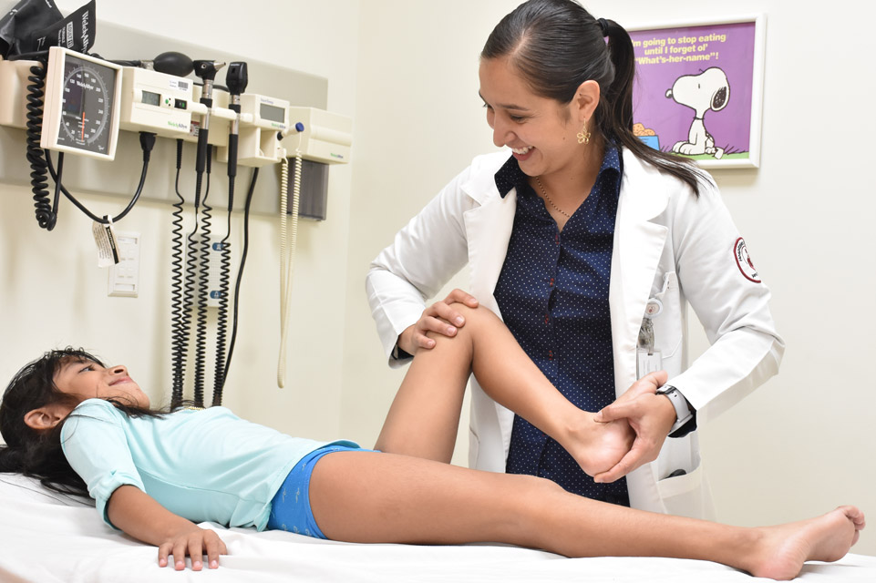 Doctora sosteniendo pierna de paciente de blusa y short azul