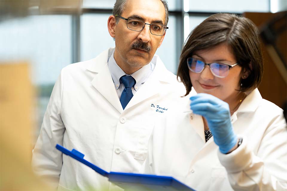 Male and female research professionals in lab looking at slide