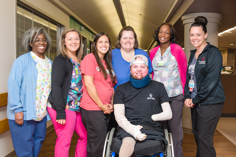 patient sitting in wheelchair with six staff members