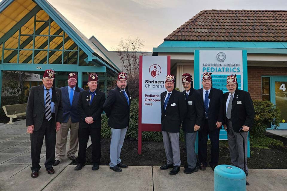 eight Shriners stand in front of Medford clinic building