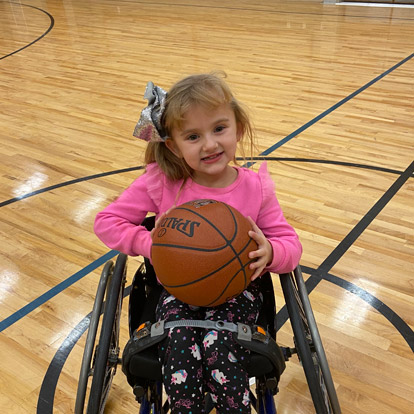 une patiente en fauteuil roulant tenant un ballon de basketball