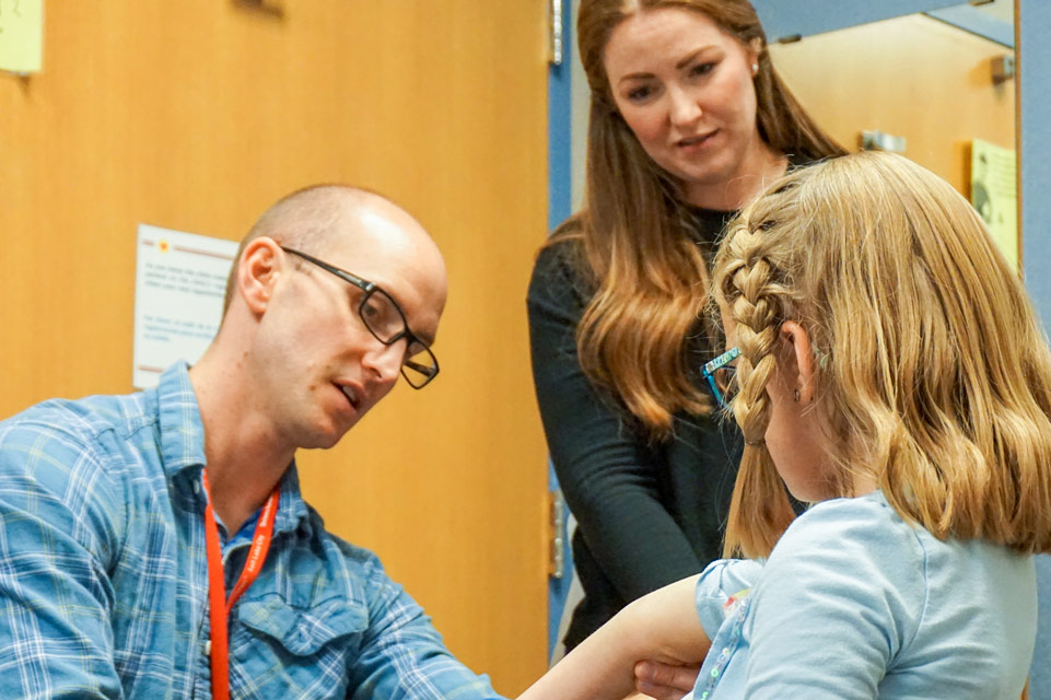 physician examines patient while mom observes