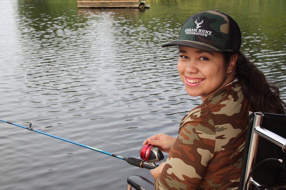 Smiling girl in wheelchair fishing