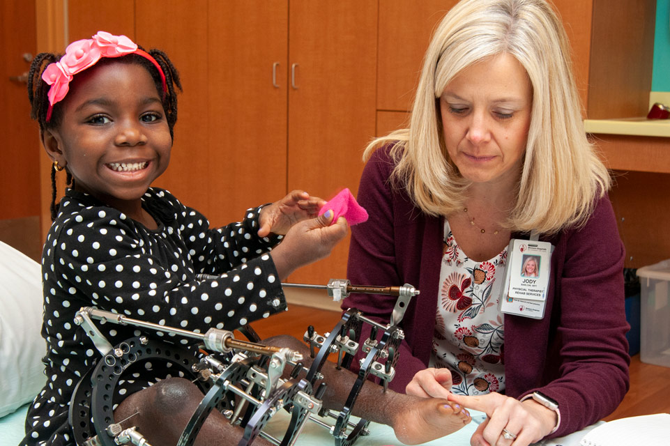 patient with both legs in ilizarov frames with staff member