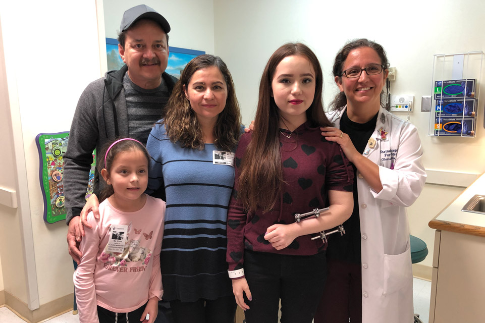 paciente con fijadores de brazo, familia y médico