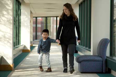 maman et patient se tenant les mains en marchant dans le hall