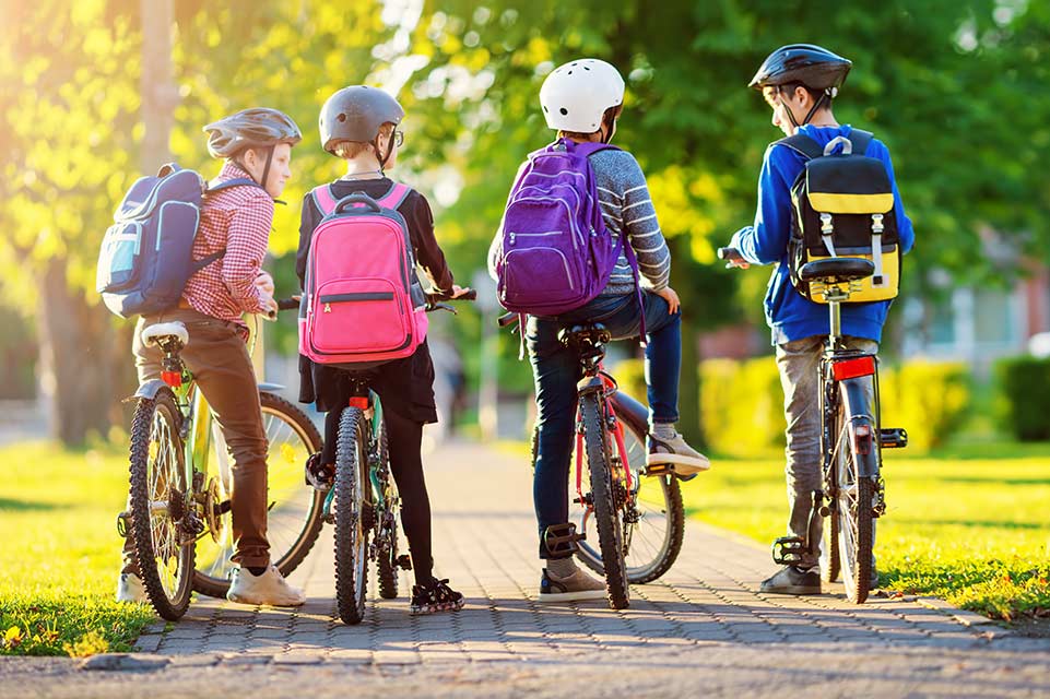 Niños con mochilas en bicicleta