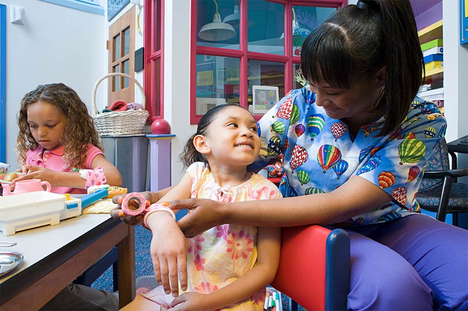 enfermera escolar vendando el brazo de un niño