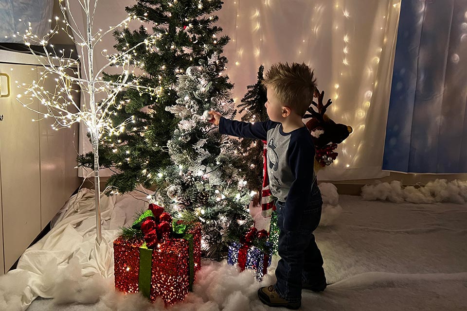 Niño colgando adornos de Navidad en el árbol