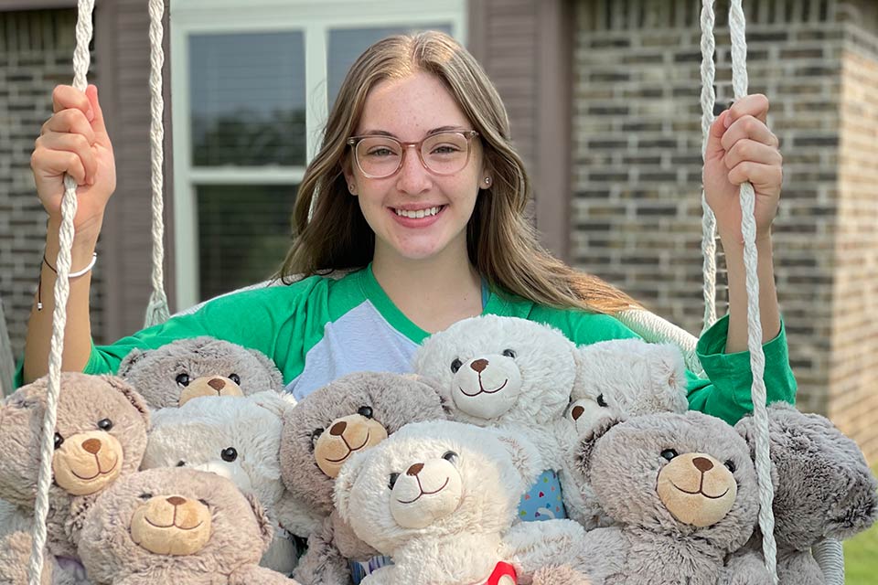 Sydney on a swing with stuffed bears on her lap