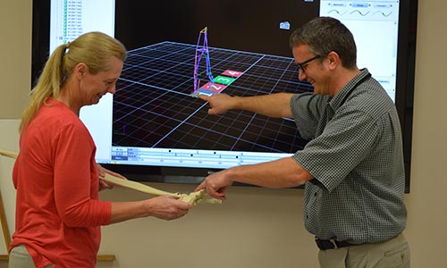 two researchers working, technical image behind them 