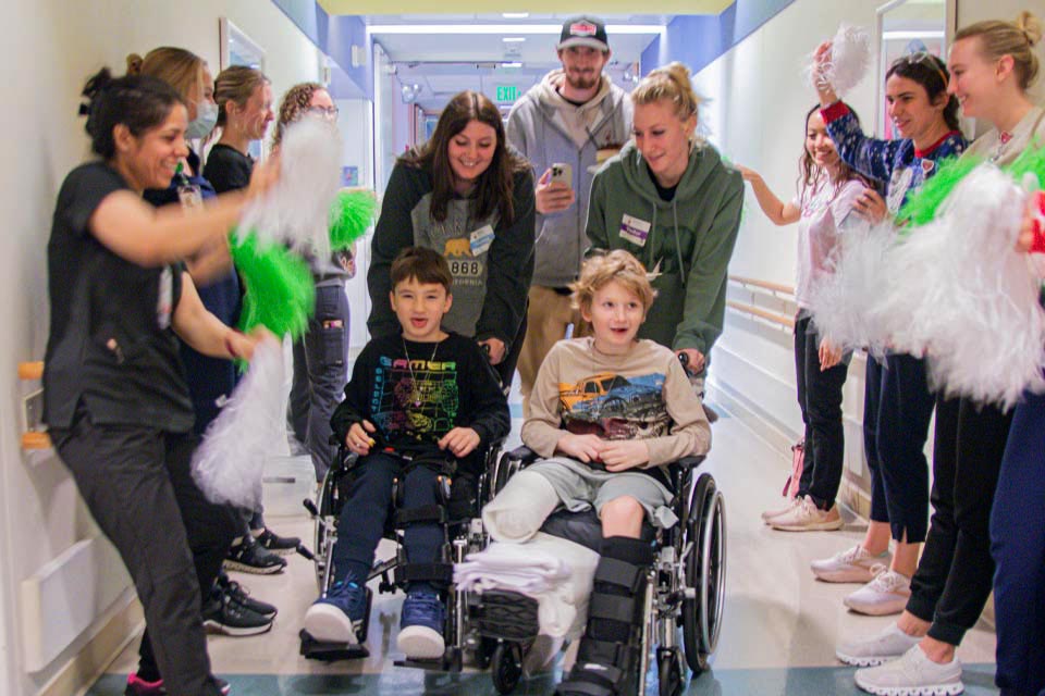 patients in wheelchairs and staff celebrating in hallway with pom poms