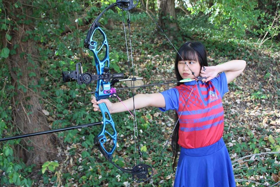 Kiera with bow and arrow, lined up for archery shot