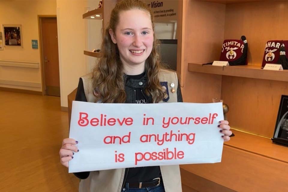 Julie tenant un livre blanc avec une citation qui dit « Croyez en vous et tout sera possible »