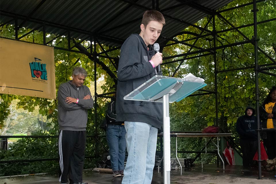 Jesse prononçant un discours, bannière Walk for Love avec logo en arrière-plan