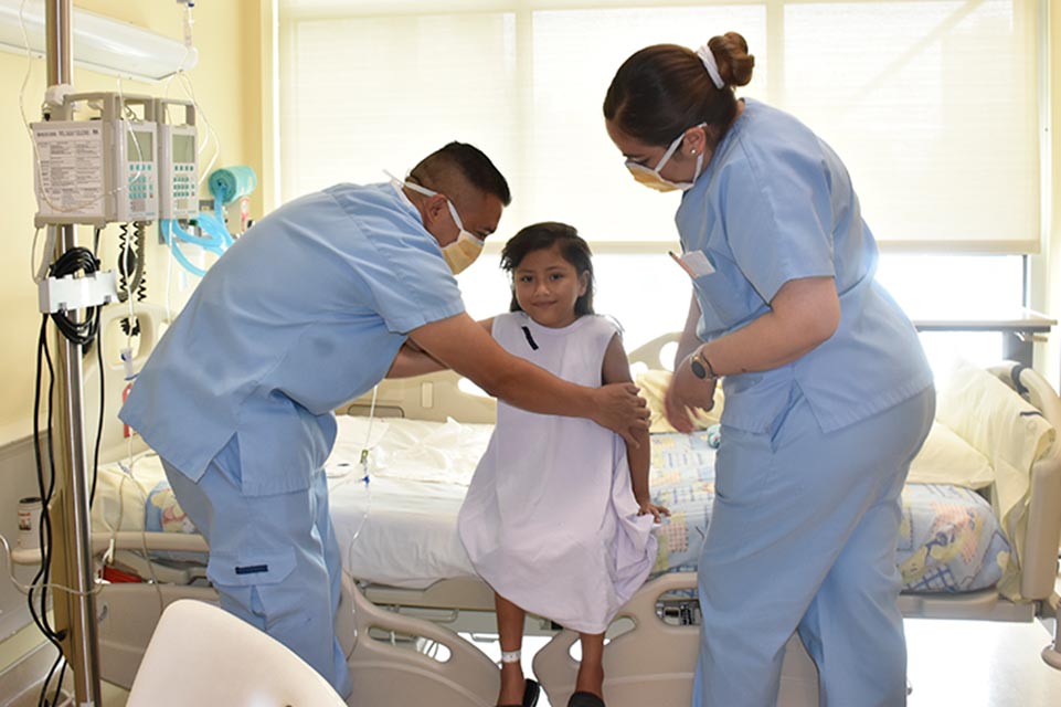 Ju Anne with two staff members helping her