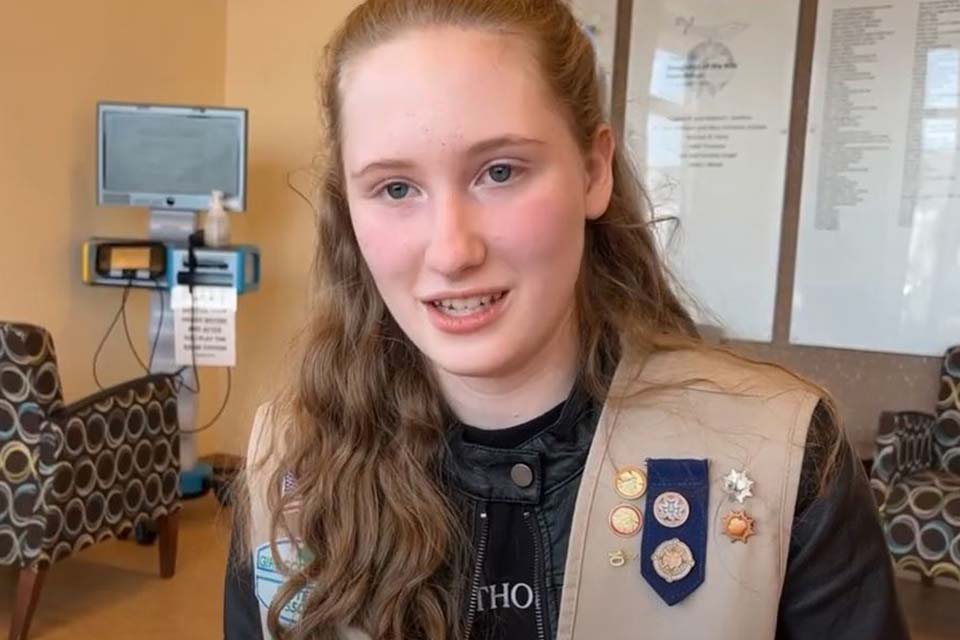 Julie, avec une veste de scout, est assise et parle