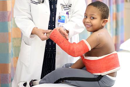 young boy smiling at camera with cast 