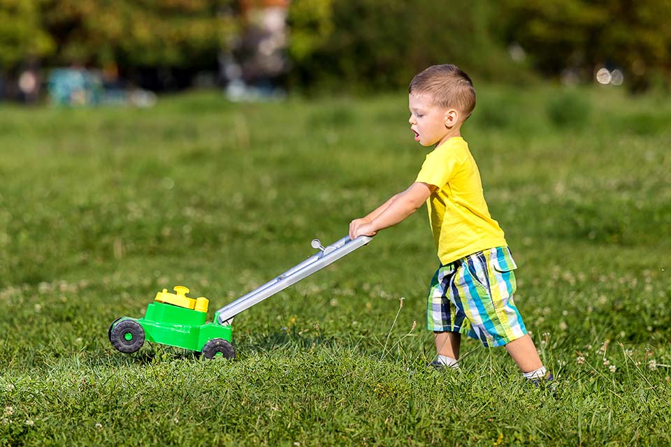 Boy pushing a toy lawnmower