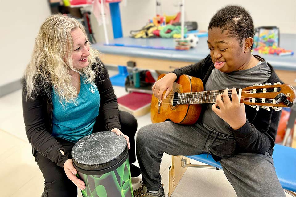 Paciente masculino tocando la guitarra con terapeuta especialista en la primera infancia