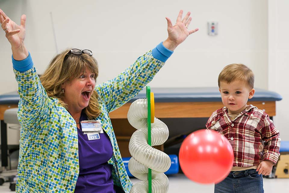 Therapist and patient sitting on floor doing therapy with red ball