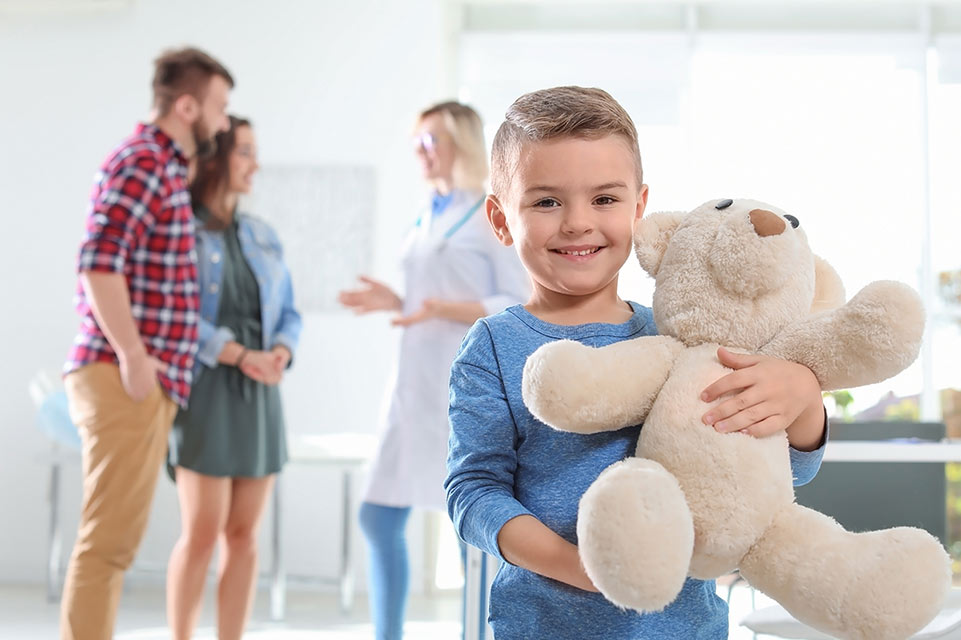 un patient tenant un ours en peluche, les parents consultent le médecin