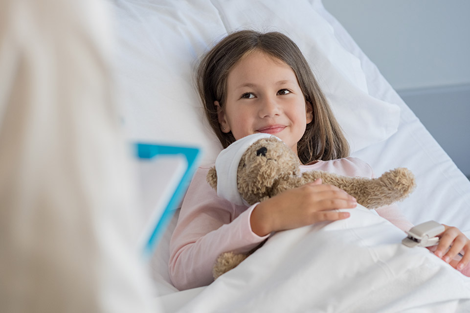 una paciente en la cama del hospital con un oso de peluche