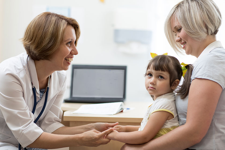 patient sitting on mother's lap, female physician