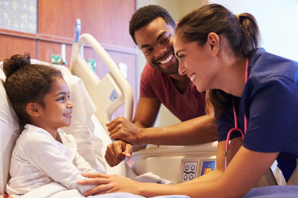 female patient in hospital bed with father and nurse