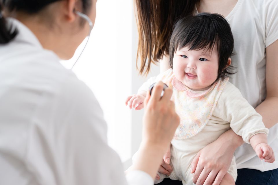 mamá con su bebé en brazos mientras el médico examina a la bebé