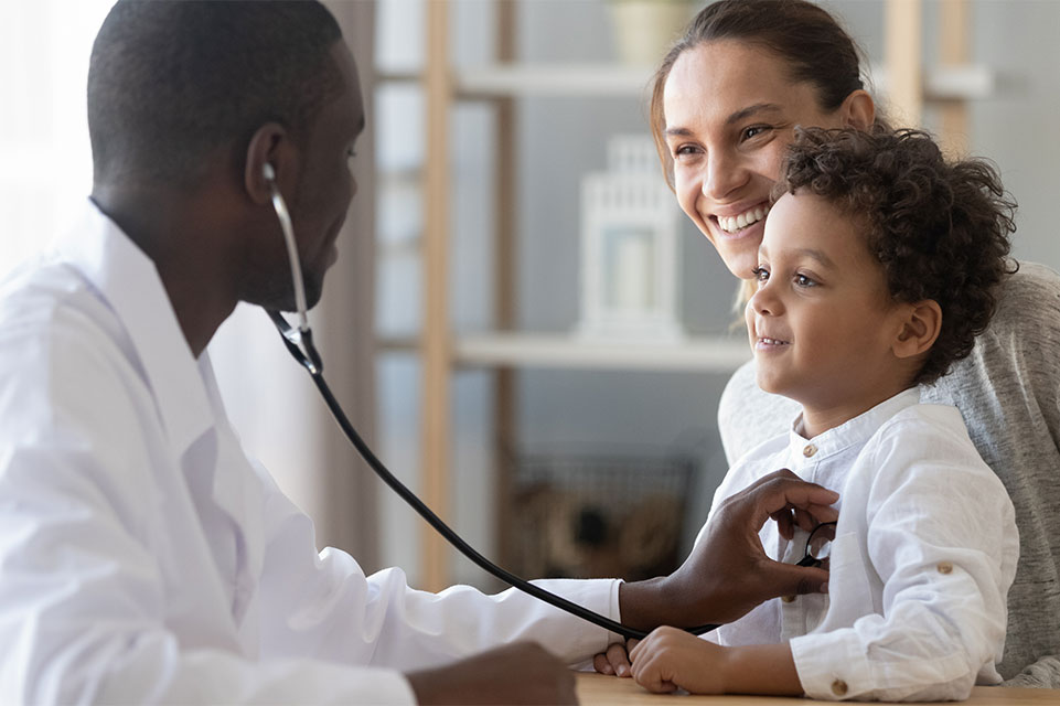 mother holds male patient, physician