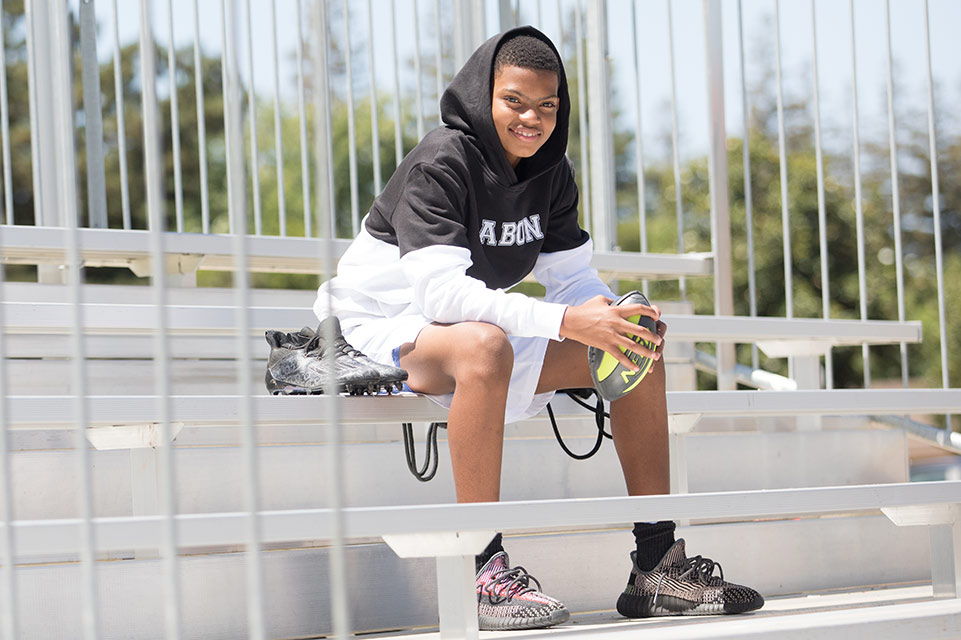 male patient sitting in bleachers holding football