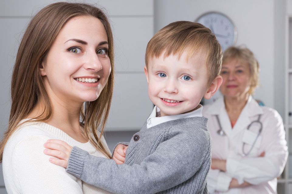 mamá sosteniendo al bebé mientras el médico mira atento