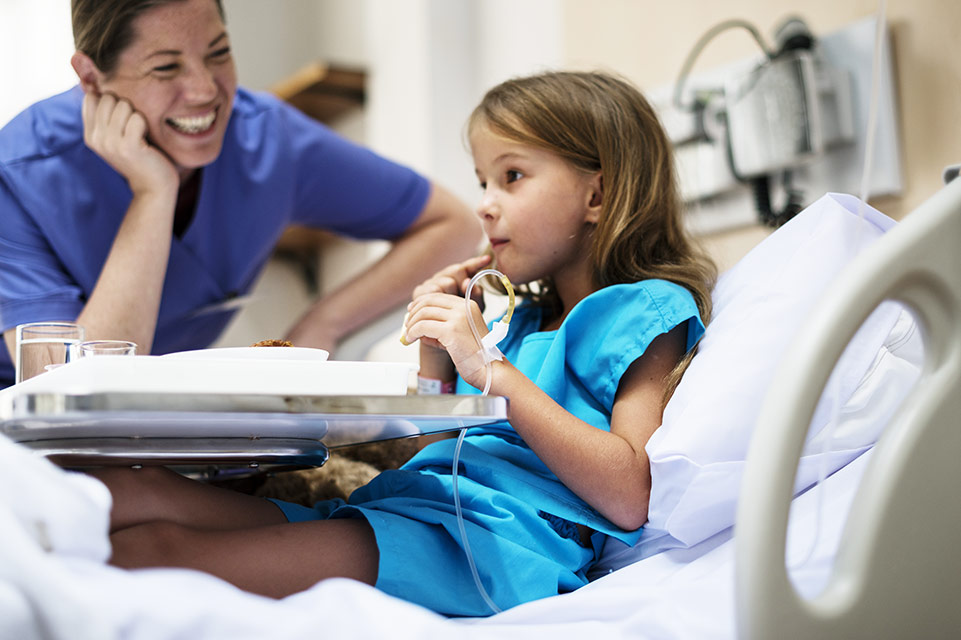 female patient in bed, nurse laughing with her