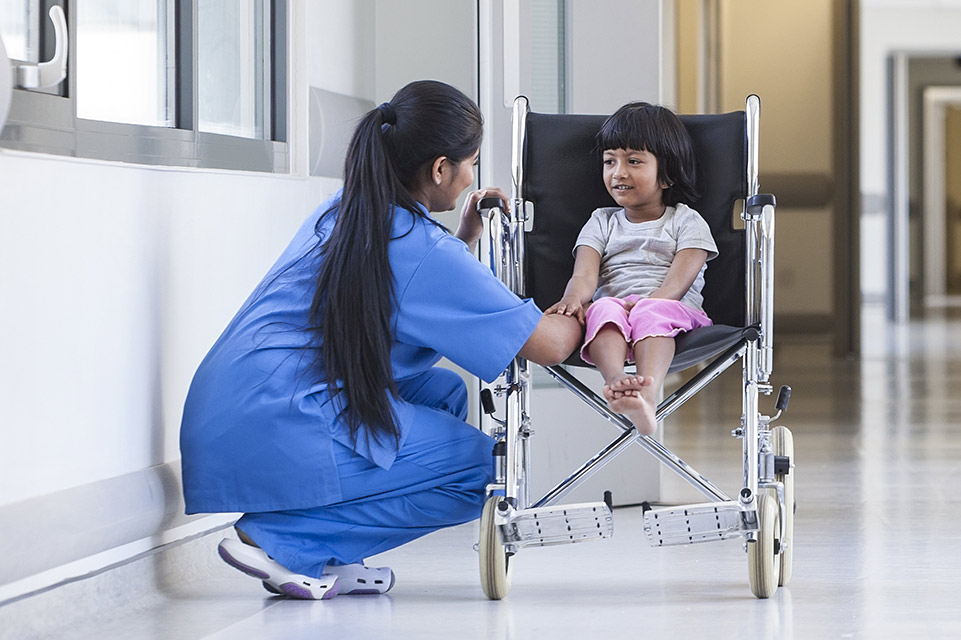 un patient en fauteuil roulant, une infirmière dans le couloir