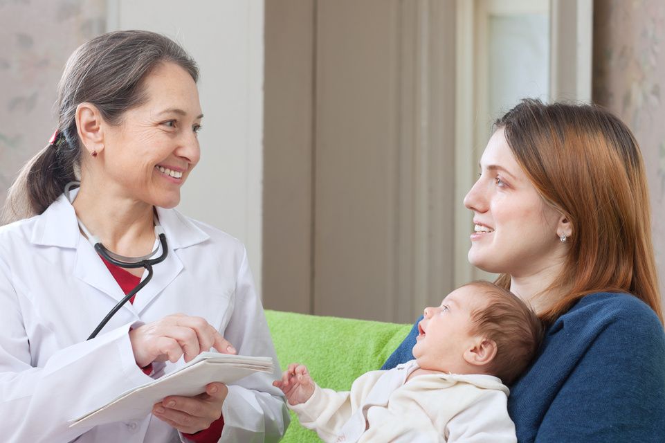 mother holding infant, speaking with physician