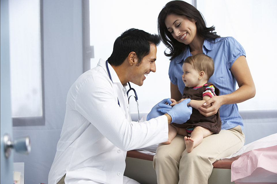 mom holds baby while physician examines him