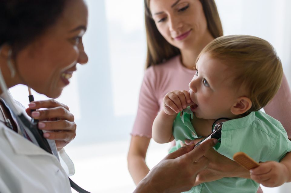 mother holds son while physician examines him