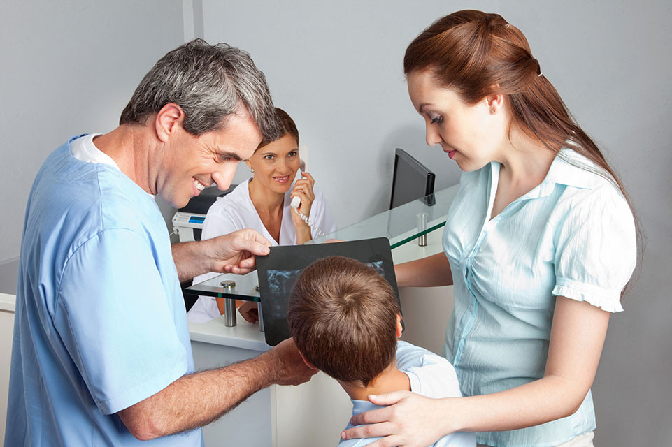 un patient, sa maman et le médecin regardant une radiographie