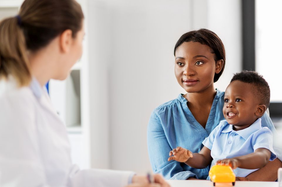 mom holds son while speaking with physician