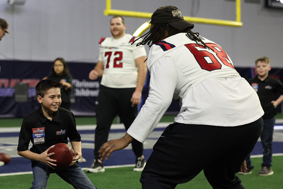 Male youth holding football and ready to run next to adult football player