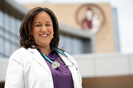 Nurse standing outside of a building with Shriners Children's logo on it